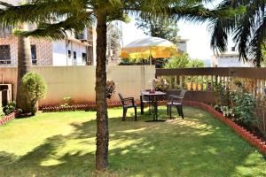 a table and chairs in a yard with a palm tree at Crescent Holiday Homes in Panchgani