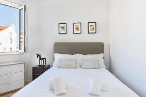 een witte slaapkamer met een bed en een raam bij ALTIDO Cosy 1-bed flat with seaview in Alfama in Lissabon