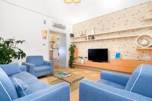 a living room with blue chairs and a tv at Unconventional Sorrento Coast in Sant'Agnello