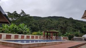 a swimming pool with a gazebo next to a mountain at HOTEL CANTINHO DAS FLORES in Guaramiranga