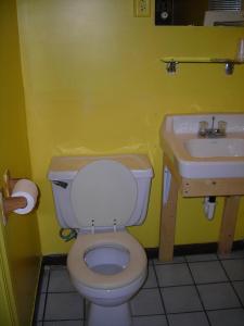 a yellow bathroom with a toilet and a sink at Hollywood Motel in Kenova