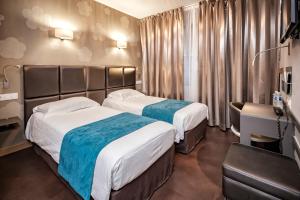 een hotelkamer met 2 bedden en een bureau bij Hôtel d'Orléans in Orléans