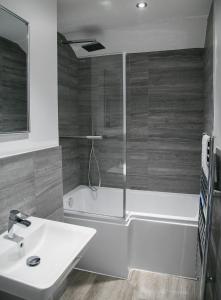 La salle de bains est pourvue d'une baignoire, d'un lavabo et d'une douche. dans l'établissement Alpha Spa classic 1 bedroom apartment, à Harrogate