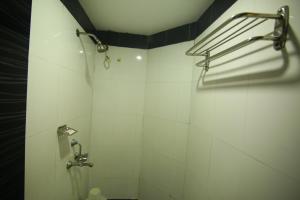 a bathroom with a shower with white tiles at Hotel White Mount in Chennai