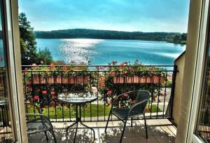 a balcony with a table and chairs and a view of a lake at RIVA Ośrodek Wypoczynkowy in Więcbork