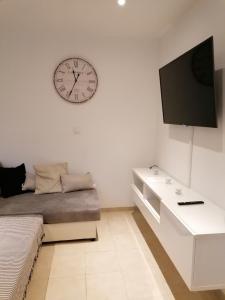 sala de estar con sofá y reloj en la pared en Appartement T2 Rez de villa proche bord de mer, en Le Pradet