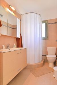 a bathroom with a toilet and a shower curtain at Cozy Sunset House in Aegina Town