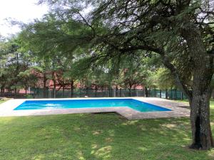 a swimming pool in a park with a tree at Casa de Veraneo en Villa La Bolsa in Villa Anizacate