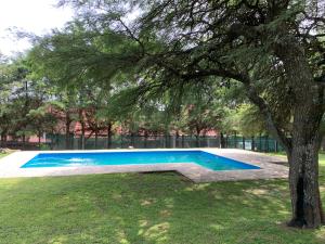 una piscina en un parque con un árbol en Casa de Veraneo en Villa La Bolsa en 