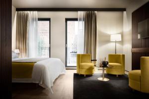 Speronari Suites في ميلانو: غرفة نوم بسرير وكرسيين اصفر