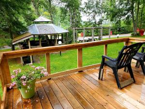 una terraza de madera con cenador y silla negra en High Falls Motel & Cabins en Wawa