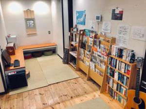 a library with books on shelves and a guitar at ゲストハウス栞庵 in Kyoto