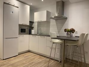a kitchen with white cabinets and a table and a refrigerator at VUT La Plaza in El Barraco