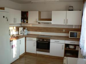 uma cozinha com armários brancos e um forno com placa de fogão em Chata Pod Hájkem em Vrchlabí