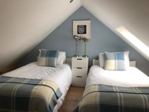 two beds in a attic bedroom with blue walls at Beautiful Coastal Cottage in Pittenweem in Pittenweem