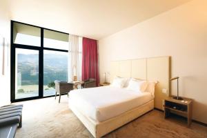 a bedroom with a large white bed and a desk at Douro Palace Hotel Resort & SPA in Baião