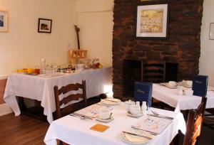 a dining room with two tables and a fireplace at The Cottage B&B in Porlock