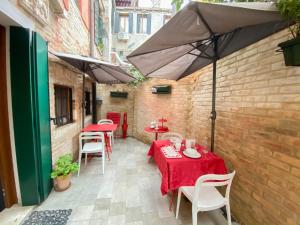 d'une terrasse avec des tables, des chaises et un parasol. dans l'établissement Rosso Charm B&B, à Venise