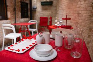 une table rouge avec des assiettes et de la vaisselle sur un tissu de table rouge dans l'établissement Rosso Charm B&B, à Venise