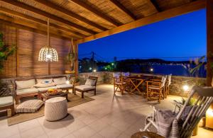 an outdoor patio with a table and chairs at night at Syros Luxury Seaview Wellness Suite Finikas in Finikas