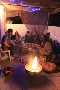 a group of people sitting around a fire in a room at Surf Therapy Morocco in Agadir