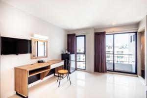 a room with a desk and a television and windows at Aliz Hotel in Nonthaburi