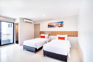 2 camas en una habitación con paredes blancas y almohadas rojas en Aliz Hotel en Nonthaburi