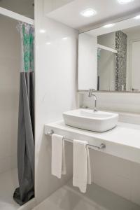 Baño blanco con lavabo y espejo en Passeio das Palmeiras, en Búzios