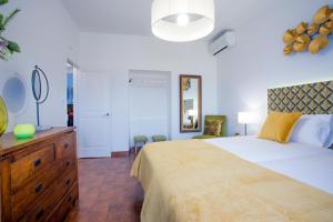 a bedroom with a large bed with a dresser and a mirror at Casa Bom Dia in Sintra