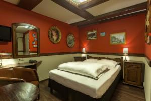 a room with a bed, a desk and a painting on the wall at A-Train Hotel in Amsterdam