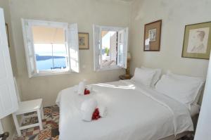 a bedroom with a white bed and two windows at Villa Fegari in Firostefani