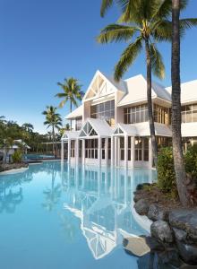 a large white swimming pool with a large blue umbrella at Sheraton Grand Mirage Resort, Port Douglas in Port Douglas