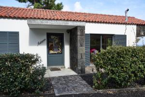 uma casa branca com persianas azuis e uma porta em Villa 4 Seasons em São Roque do Pico