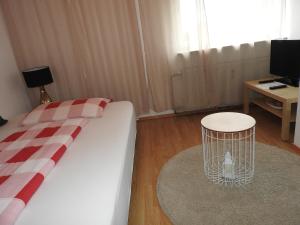 Schlafzimmer mit einem Bett, einem Tisch und einem TV in der Unterkunft Warmbad Apartments in Villach