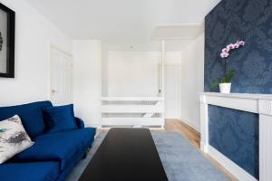 sala de estar con sofá azul y chimenea en The Bluebird - One Bedroom Apartment in Watford en Watford