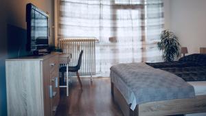 a bedroom with a bed and a dresser with a television at Viola Apartman Pécs in Pécs