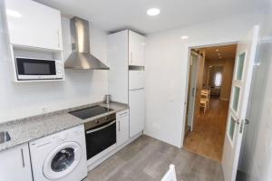 a white kitchen with a washer and a microwave at Bonito Apartamento en Santander in Santander