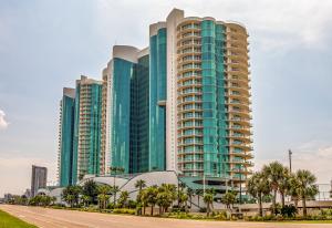 wysoki budynek z palmami przed nim w obiekcie Turquoise C1507 w mieście Orange Beach