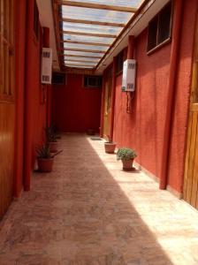 un couloir vide d'un bâtiment aux murs rouges dans l'établissement Hostal Chaxa, à San Pedro de Atacama