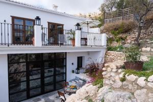 a white house with black windows and a stone wall at Casa Higueras in Moclín