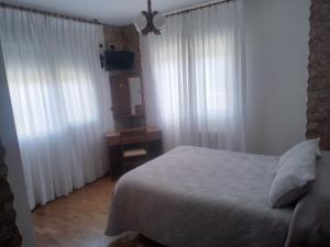 a bedroom with a bed with white curtains and a mirror at Hotel Arume in Bóveda