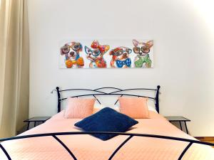 City-Maisonette في فيينا: غرفة نوم مع سرير مع أربع لوحات للكلاب على الحائط