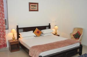 a bedroom with a bed with two lamps and a chair at Rampura Kothi in Jaipur