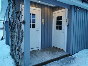 Arctic Gourmet Cabin في كيرونا: البيت الأزرق والأبواب البيضاء في الثلج