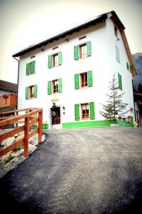 a large white building with green windows and a fence at Agriturismo Plan Da Crosc in Prato Carnico