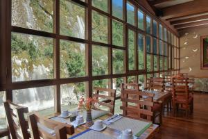 ein Esszimmer mit Tischen, Stühlen und großen Fenstern in der Unterkunft Casa del Sol Machupicchu in Machu Picchu