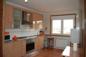 a kitchen with wooden cabinets and a white refrigerator at La Casa de Lines in Monforte de Lemos