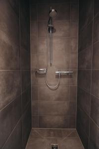 La salle de bains est pourvue d'une douche avec du carrelage brun. dans l'établissement Boardinghouse Sorgenfrei, à Hagen