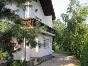 Una casa blanca con un árbol delante. en Viola Vendégház en Kehidakustány