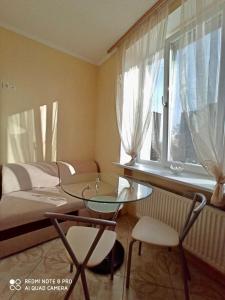een kamer met een glazen tafel en stoelen en een bed bij Apartment in the center in Tsjerkasi